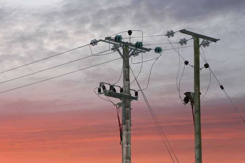 Two electricity pylons, in a rural location, photographed against a red sky. Two electricity pylons, in a rural location, photographed against a red sky.