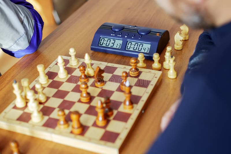 An electronic chess clock and a chessboard with pieces are on the table