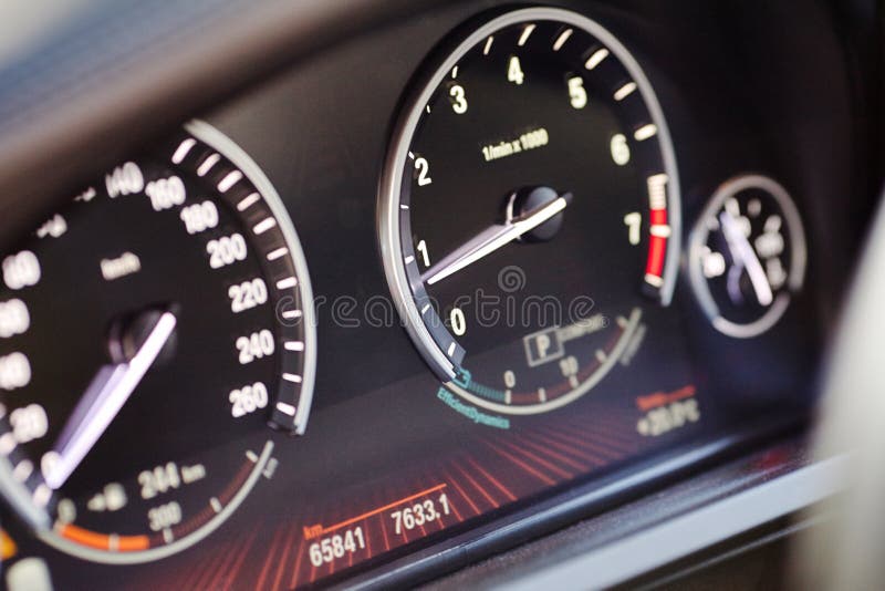 Electronic dashboard of modern luxury car view from aside. Speedometer blurred with selective focus on the arrow and tachometer