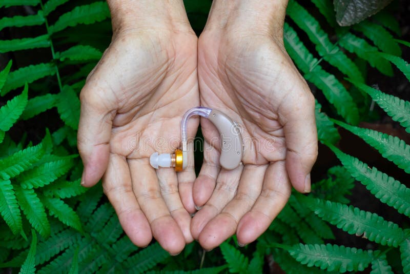 Electronic hearing aid device in the ear of Asian old man with total deafness