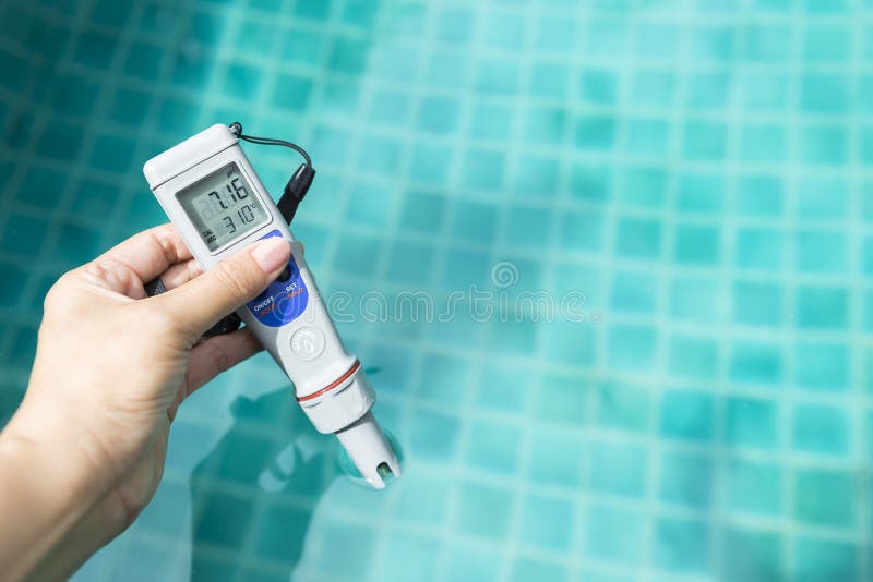 Electronic water testing meter in girl hand over blurred blue swimming pool water background, summer outdoor day light