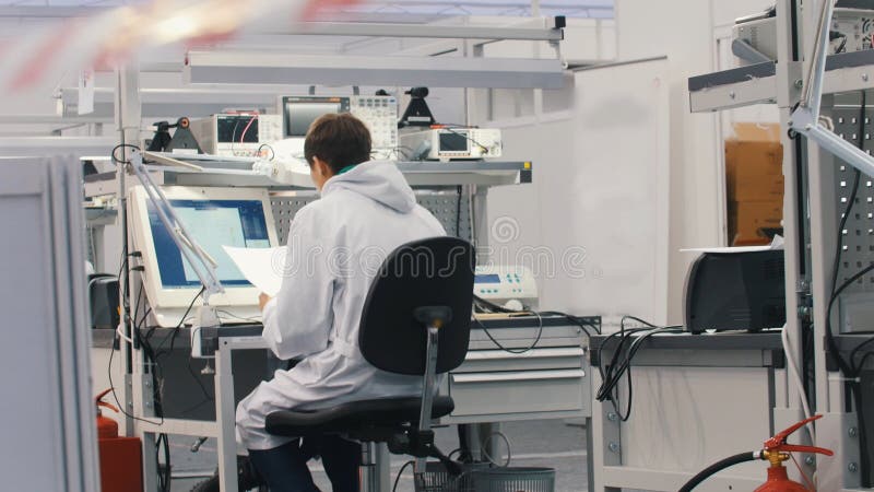 Electronics engineers working in lab. Engineers sitting at the table and working on the computer. Back overview