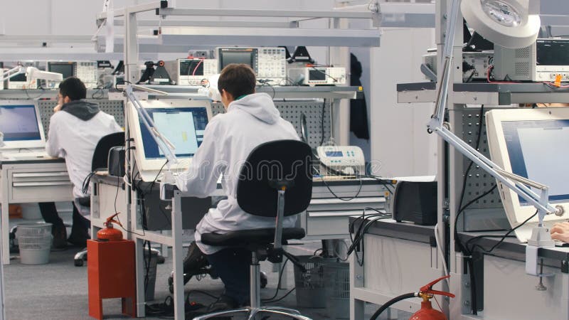 Electronics engineers working in lab. Engineers sitting at the table and working on the computer. White office overview