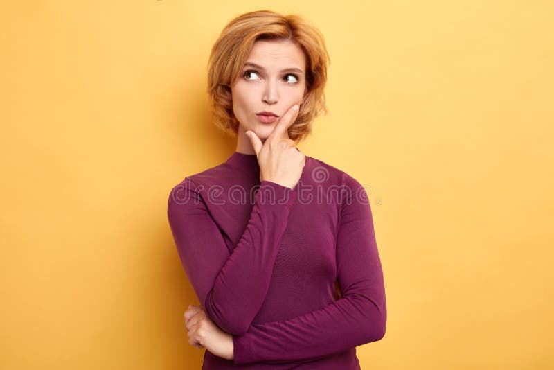 Elegancka młoda jasnogłowa kobieta dotyka jej podbródek i patrzeje daleko od fotografia stock Elegancka młoda jasnogłowa kobieta dotyka jej podbródek i patrzeje daleko od fotografia stock