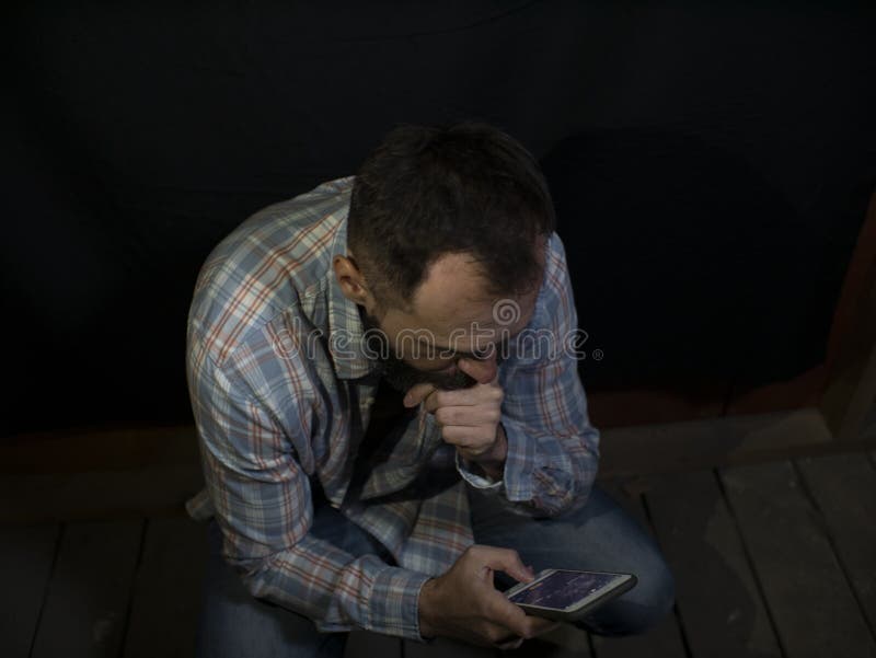 Elegancki mężczyzna z brodą i wąsy kucania spojrzenia przy telefonu komórkowego ekranem obrazy stock Elegancki mężczyzna z brodą i wąsy kucania spojrzenia przy telefonu komórkowego ekranem obrazy stock