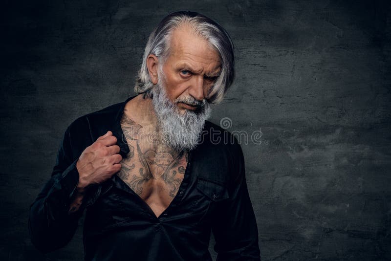 Elegancki starszy kulturysta, gapiący się w kamerę na ciemnym tle fotografia royalty free