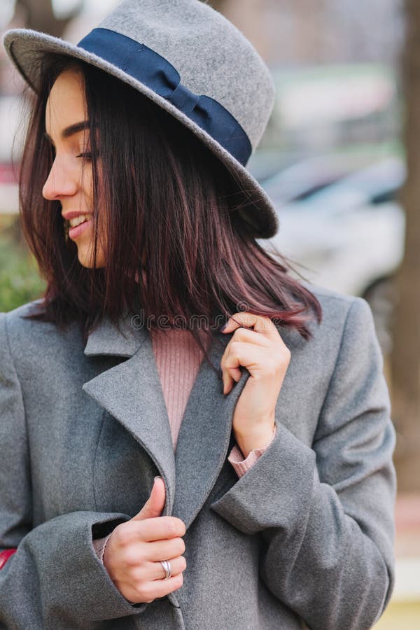 Eleganckiego eleganckiego wizerunku radosna młoda kobieta ono uśmiecha się popierać kogoś na ulicie z brunetka włosy w popielatym fotografia stock