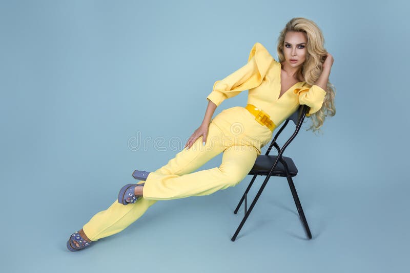 Elegant blond kvinna i stilfull gul jumpsuit och trendig tillbehör på färgbakgrund H?rlig modemodell p? bl?tt royaltyfria foton Elegant blond kvinna i stilfull gul jumpsuit och trendig tillbehör på färgbakgrund H?rlig modemodell p? bl?tt royaltyfria foton