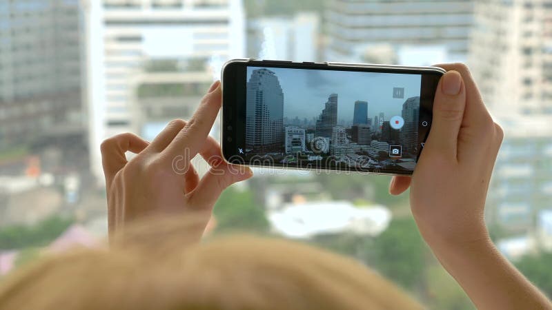Elegant blonde woman making a photo on the phone. woman photographs the view from the window of the skyscrapers royalty free stock photos Elegant blonde woman making a photo on the phone. woman photographs the view from the window of the skyscrapers royalty free stock photos