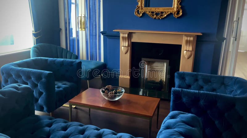 Elegant blue interior with plush velvet sofas, a refined gold-framed mirror, and a classic fireplace, capturing timeless stock video footage
