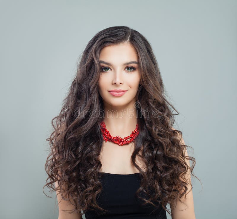 Elegant brunette woman model with makeup, curly long hair and red coral necklace