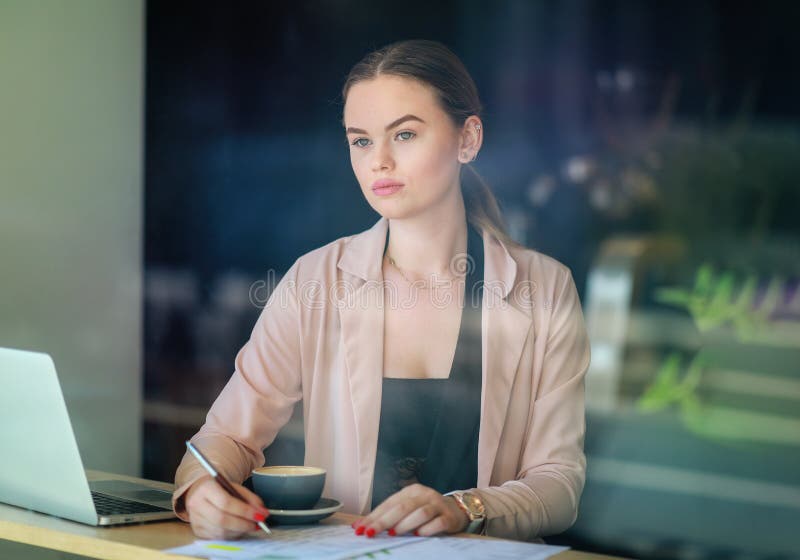 Elegant business woman looking through the window in a cafe shop. Thoughtful Look. Selective focus and reflexion on window stock images Elegant business woman looking through the window in a cafe shop. Thoughtful Look. Selective focus and reflexion on window stock images