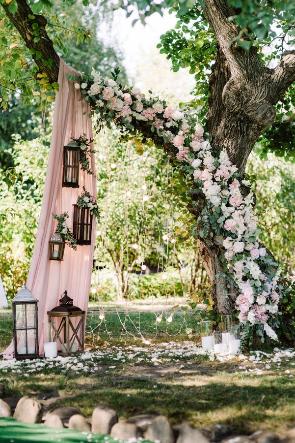 Elegant decoration of the wedding arch with fresh flowers, lights and garlands in the style of a flowering garden