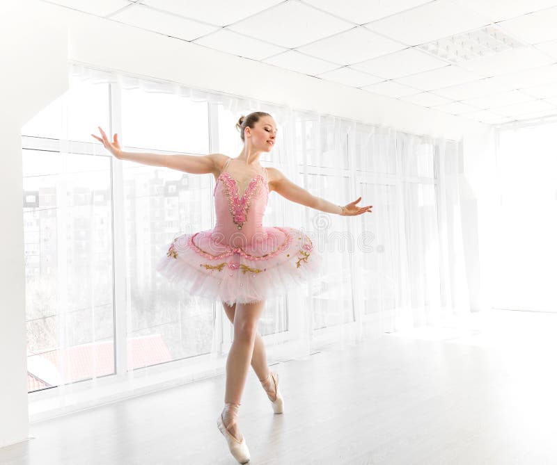 Elegant female ballet dancer in pink tutu practicing and smiling royalty free stock photo Elegant female ballet dancer in pink tutu practicing and smiling royalty free stock photo