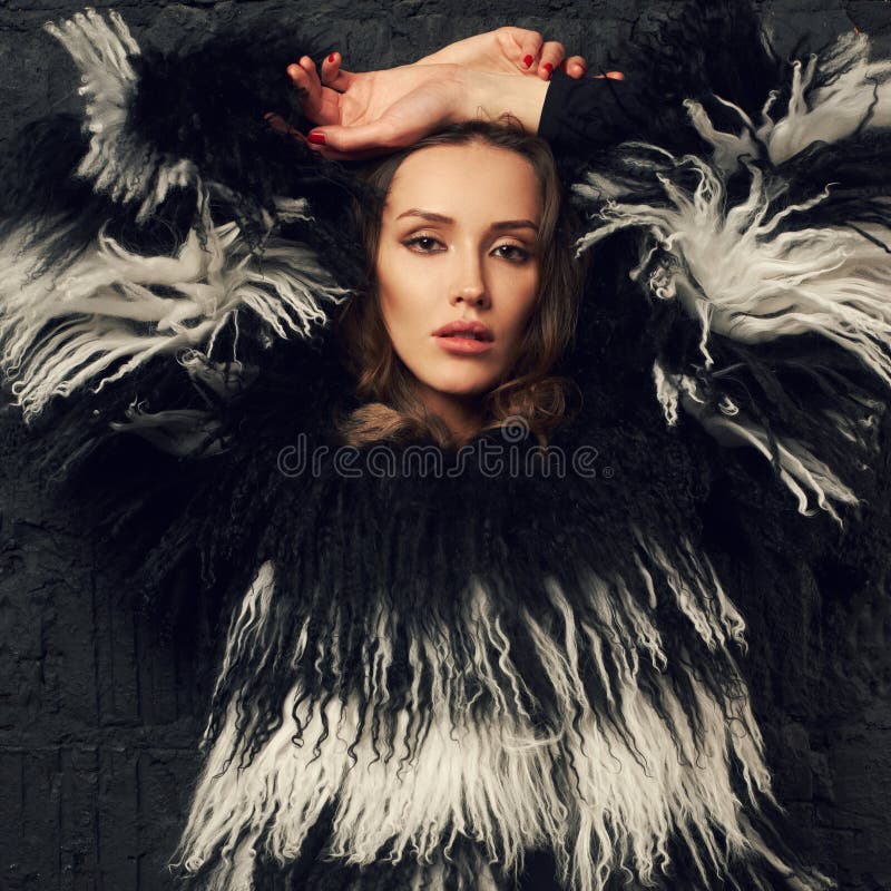 Elegant Female Model In Faux Fur Coat Posing Against Gray Brick Stock