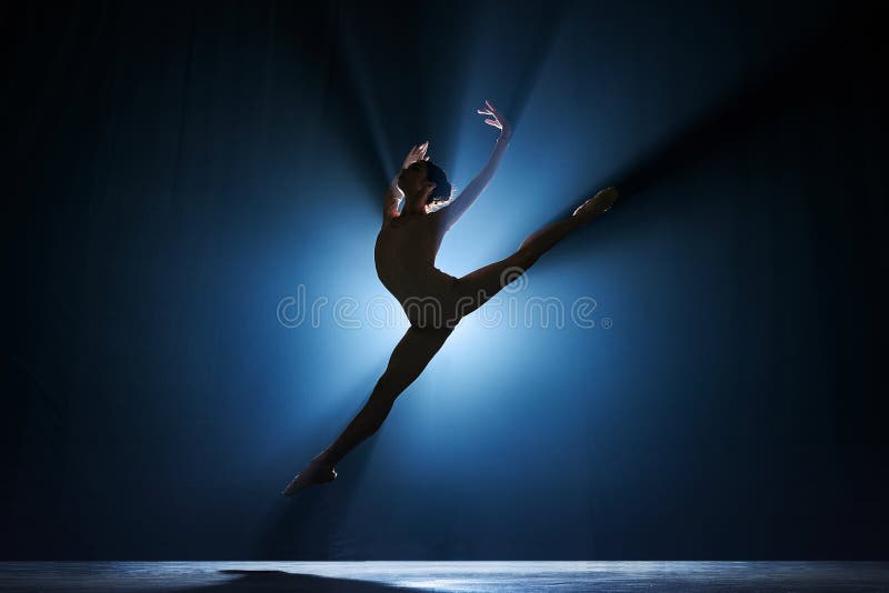 Elegant femininity. Beautiful, tender young woman, ballerina dancing against dark blue background with spotlight