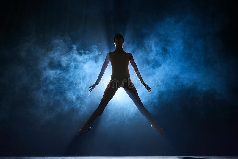 Elegant femininity. Beautiful, tender young woman, ballerina dancing against dark blue background with spotlight