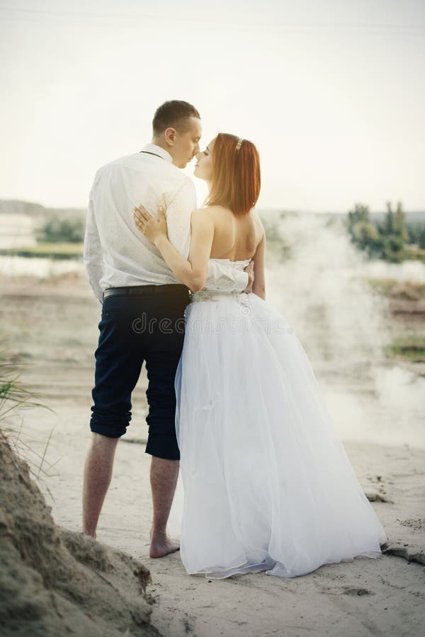 Wedding Couple Sitting On Bridge Near Lake On Sunset At Wedding Day Bride And Groom In Love