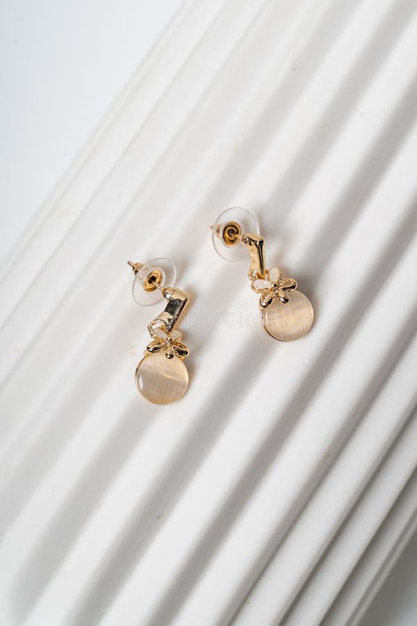 Elegant Gold Earrings on White Textured Background royalty free stock photography