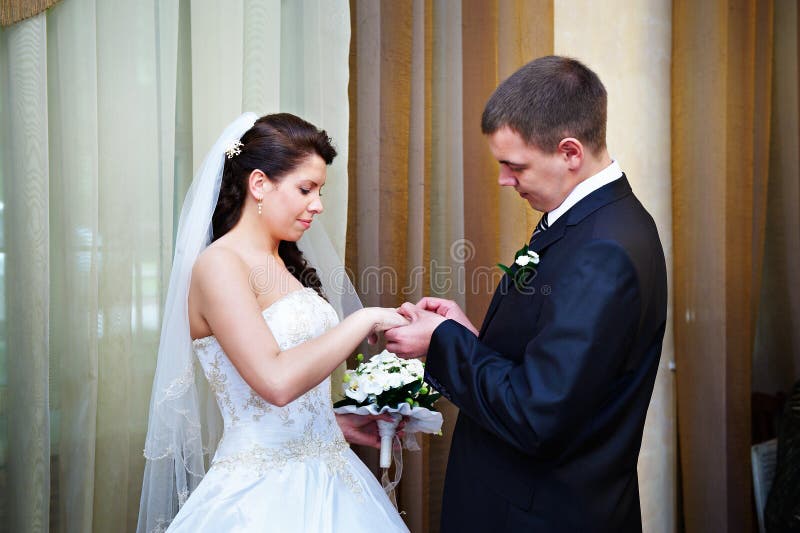 Elegant groom wears a wedding ring a happy bride