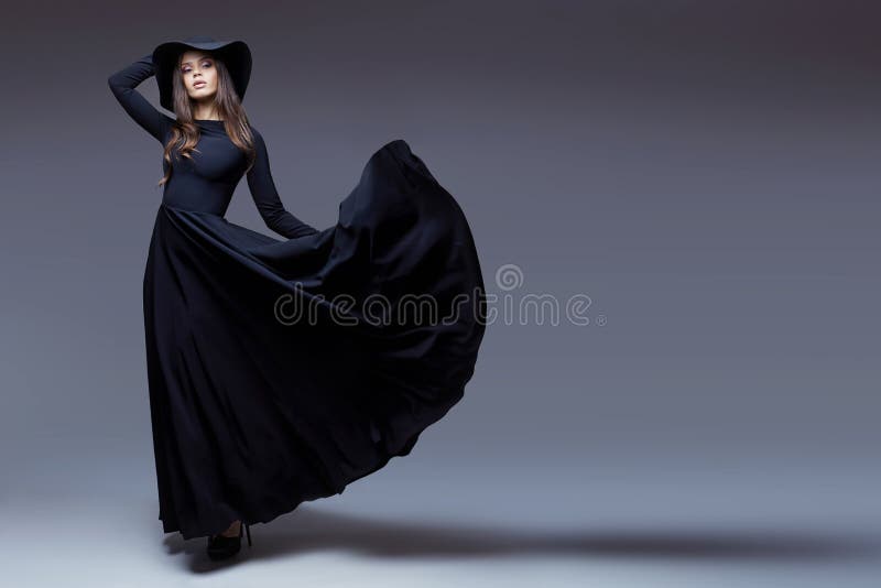Elegant kvinna i en hatt och en fladdralänge klänning fotografering för bildbyråer Elegant kvinna i en hatt och en fladdralänge klänning fotografering för bildbyråer