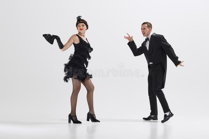 Elegant women and men in retro attire engage in fun, choreographed dance, evoking the spirit of bygone era isolated over white studio background. Concept of art, retro and vintage, entertainment, 20s. Elegant women and men in retro attire engage in fun, choreographed dance, evoking the spirit of bygone era isolated over white studio background. Concept of art, retro and vintage, entertainment, 20s