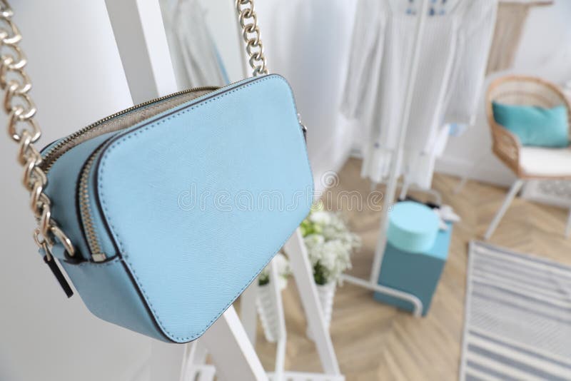 Elegant Light Blue Handbag Hanging on Rack in Dressing Room Stock Photo