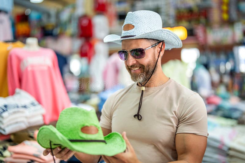Elegant man i boutique. Mature man som väljer hat. Lager för manliga tillbehör. Trendy-modebutik. Handsome man som försöker på hat arkivbilder