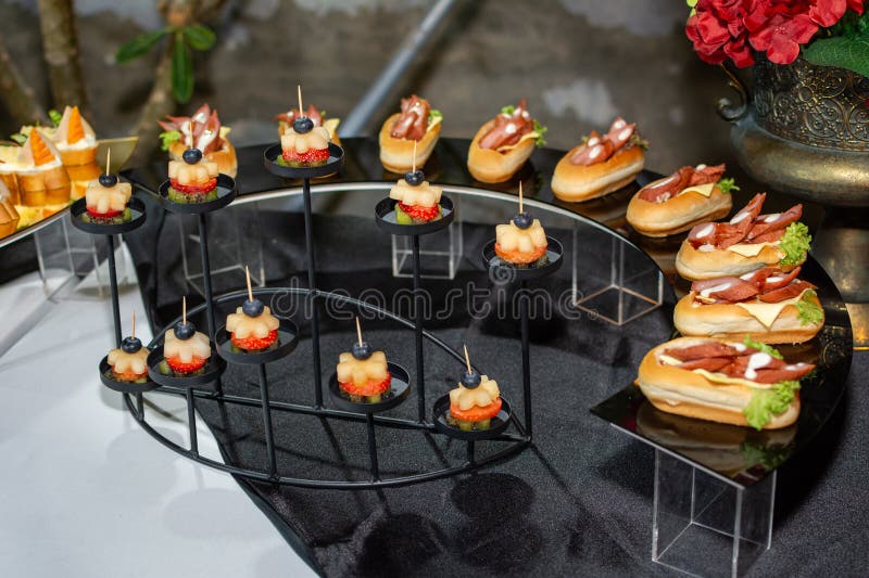 Elegant mini fruit and meat canapés are presented on a formal catering buffet display for an evening event stock photo