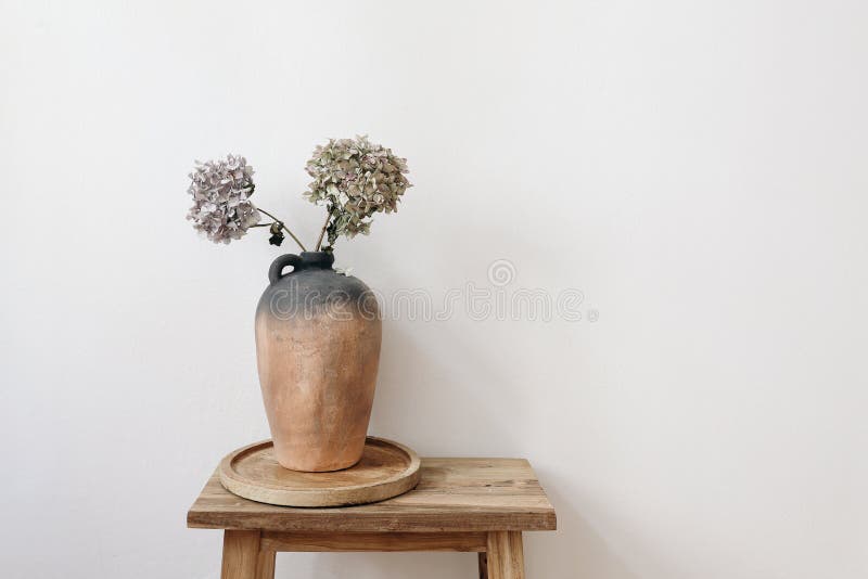 Elegant minimal summer, fall still life photo. Rustic clay vase, pitcher with hydrangea flowers on old wooden stool