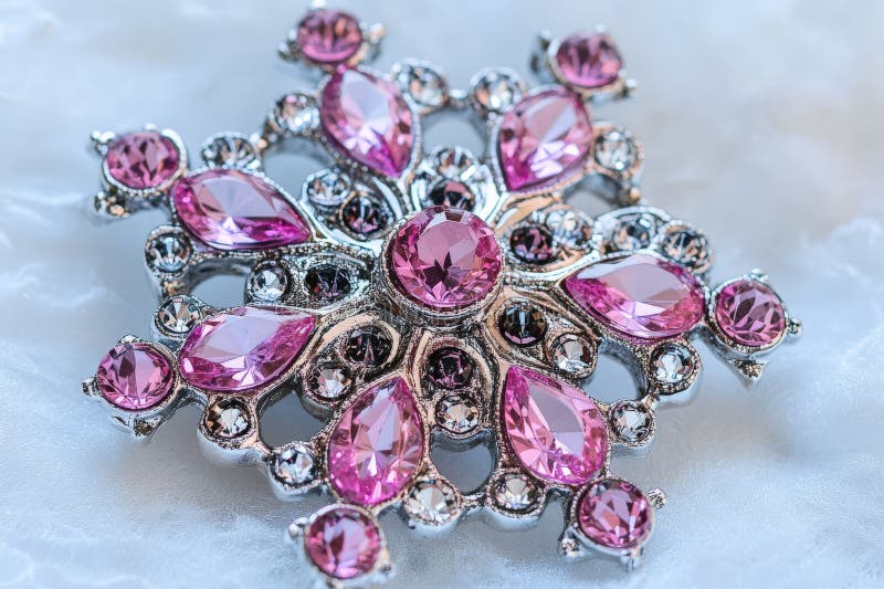 Elegant pink gemstone brooch with intricate patterns on white fabric background vector illustration