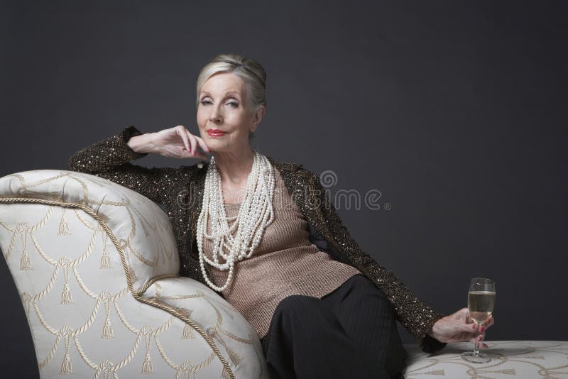 Elegant Senior Woman On Chaise Lounge With Champagne