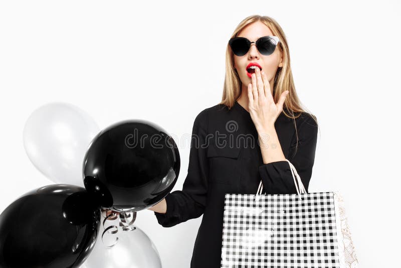 Elegant shocked girl, in black dress with sunglasses, with bags