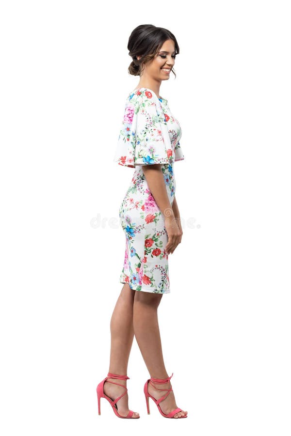 Elegant shy feminine fashion female model in floral dress smiling and looking down