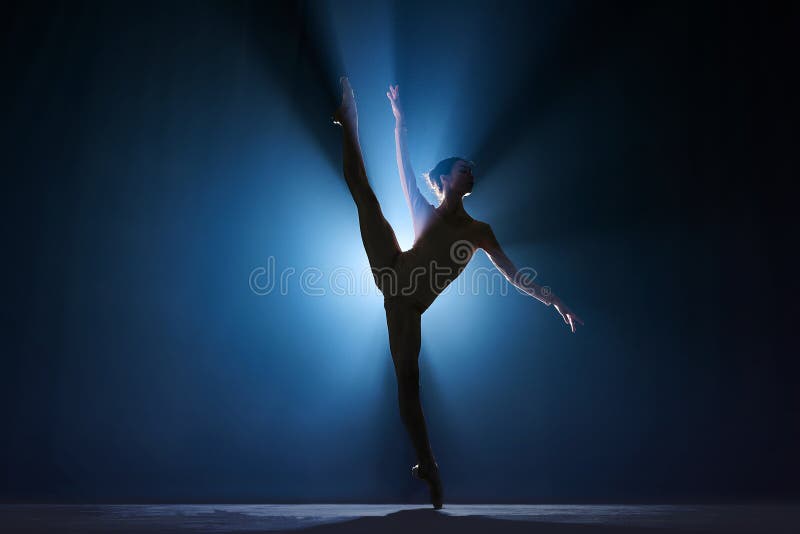 Elegant silhouette of elegant young girl, ballet dancer dancing on stage against dark blue background with spotlight