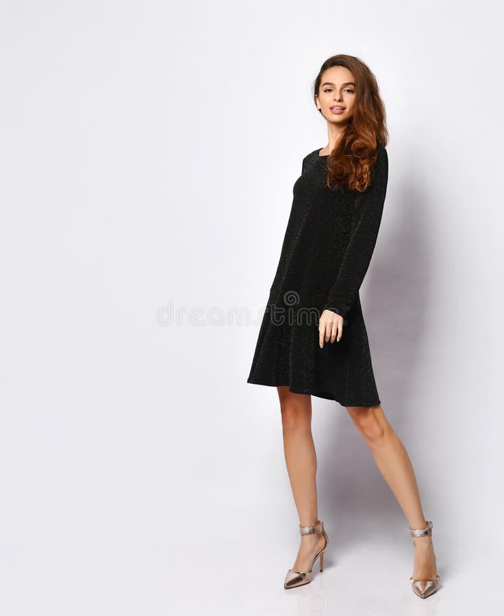 Charming Model with Flowing Dark Hair in Posh Black Dress and Silver Shoes  Posing on One Leg Holding Hand on Hip Stock Photo - Image of black, lady:  205134936