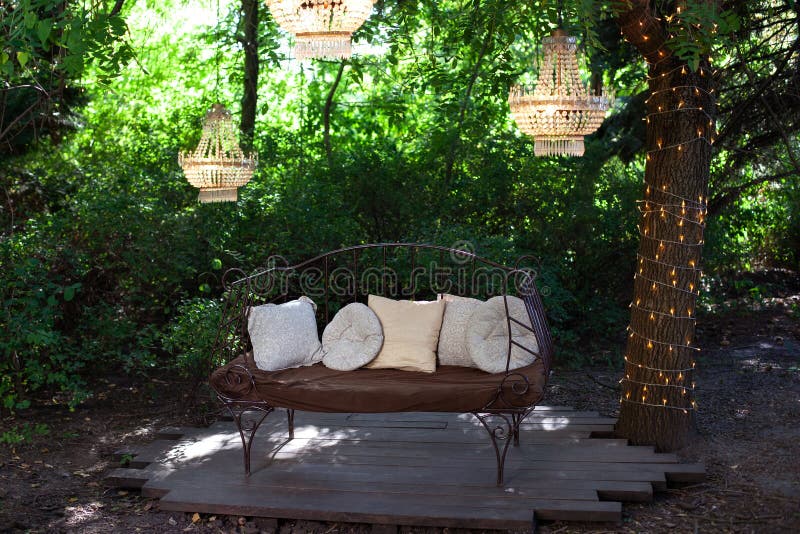 Elegant sofa i trädgårdens prydnadskomposition utomhus med tre chandeliers. vacker elegant dekör för bröllopsceremoni i vacker trädgård. blixtlås för uppmjukning utomhus. romantisk alkost