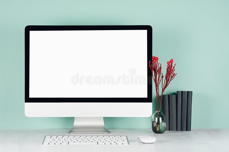 Elegant spring home workplace with blank computer screen, black books, keyboard, mouse, red plant in glass vase in green mint. royalty free stock images