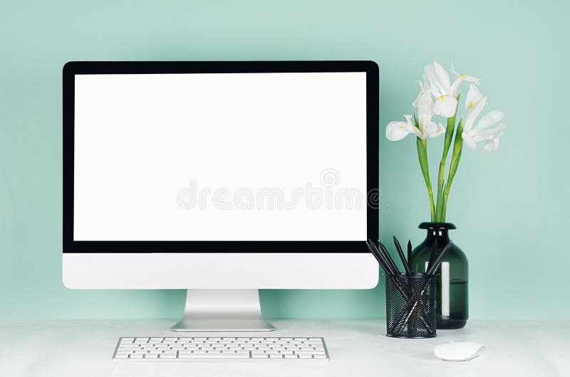 Elegant spring home workplace with blank computer screen, black stationery, keyboard, mouse, white fresh flowers in vase in green. stock photos