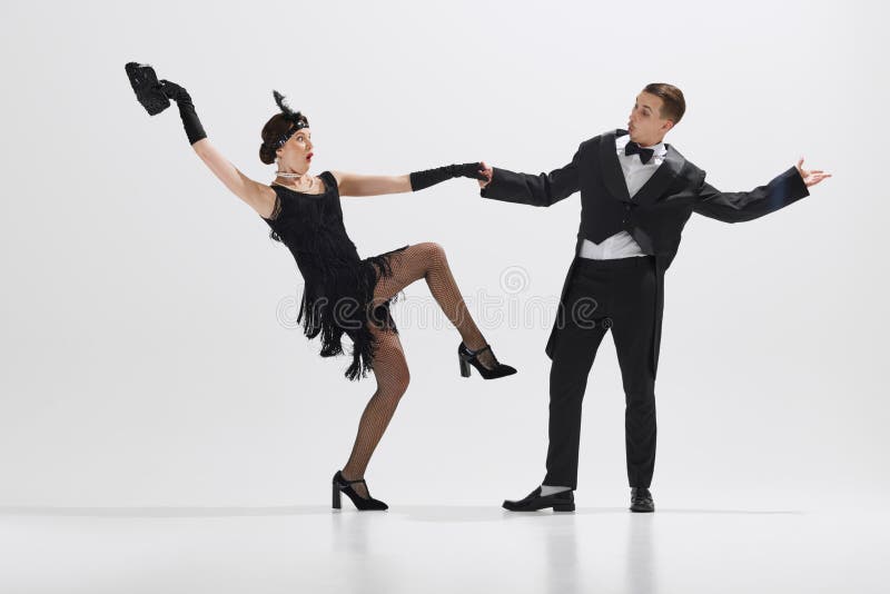 Elegant young couple performing theatrical dance typical of jazz age, demonstrating playful gestures isolated over white studio background. Concept of art, retro and vintage, hobby, entertainment, 20s. Elegant young couple performing theatrical dance typical of jazz age, demonstrating playful gestures isolated over white studio background. Concept of art, retro and vintage, hobby, entertainment, 20s