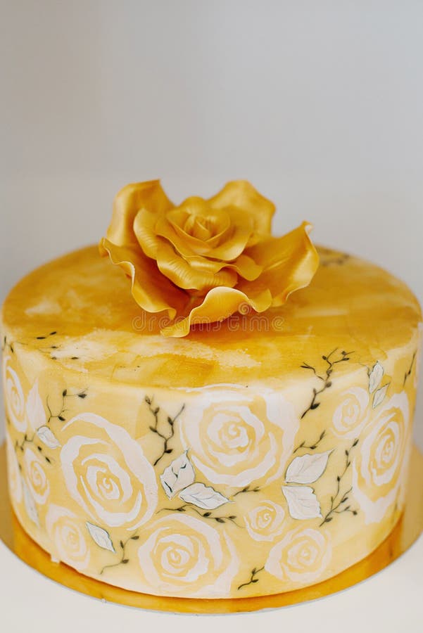 Elegant wedding cake with a large royal icing rose on top dripped in gold edible paint