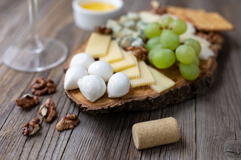 Elegant wine and cheese board with grapes and nuts on rustic wooden table stock photo