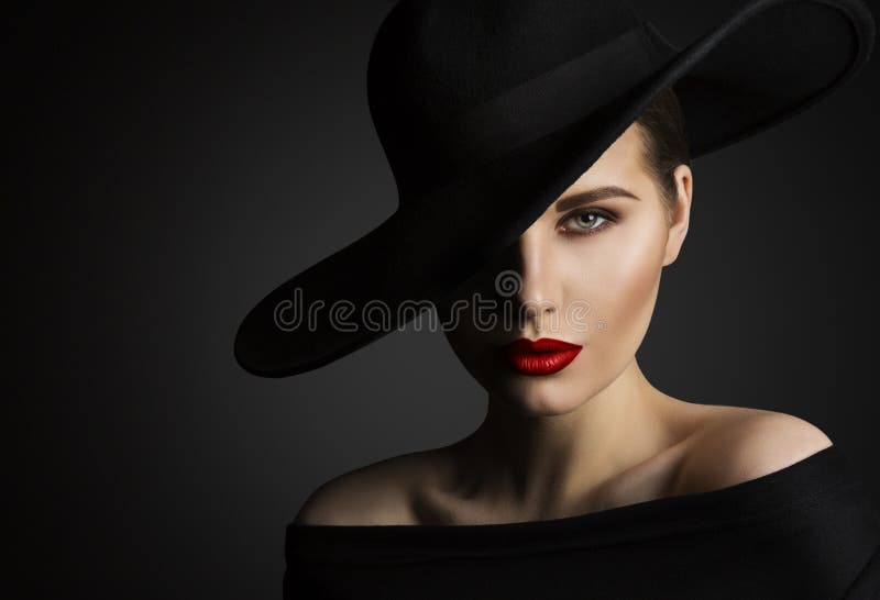 Elegant Woman Face Portrait hidden by Black Hat. Beauty Fashion Model with Red Lips and Eye Make up over dark Gray Background