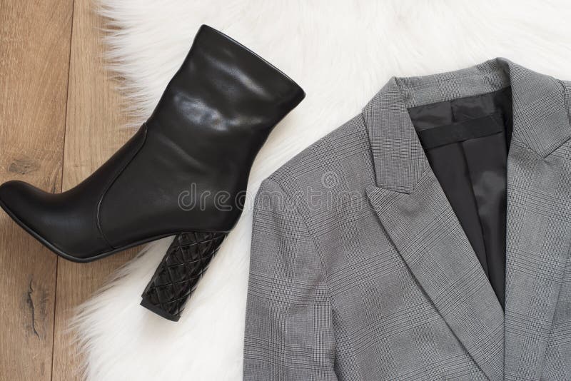 Elegant women jacket and black high heel boots. Checkered a gray jacket on a wooden background. Concept of fashion and design, sho