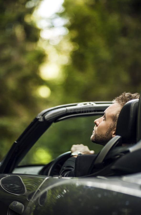 Elegant young happy man in convertible car outdoor.