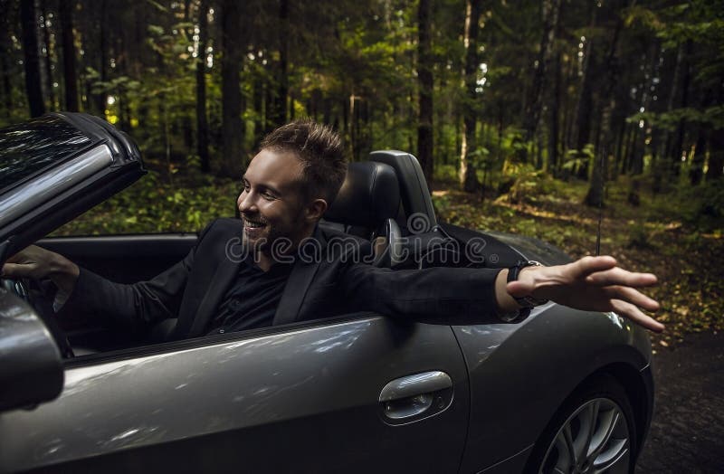 Elegant young happy man in convertible car outdoor.