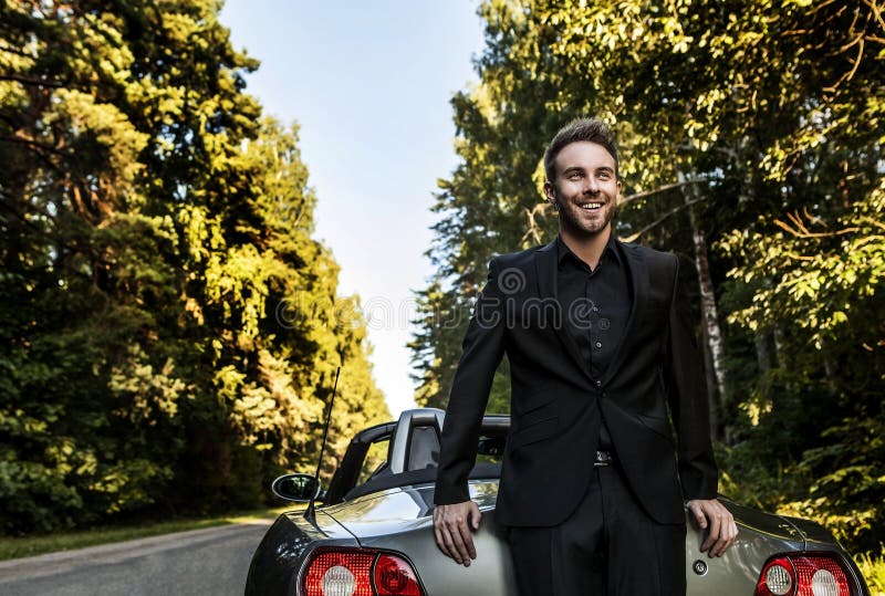 Elegant young happy man in convertible car outdoor.