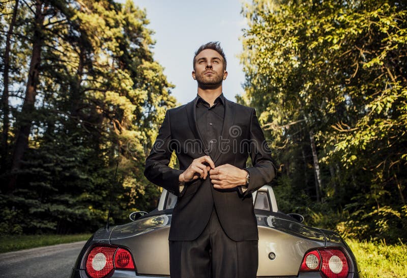 Elegant young happy man in convertible car outdoor.