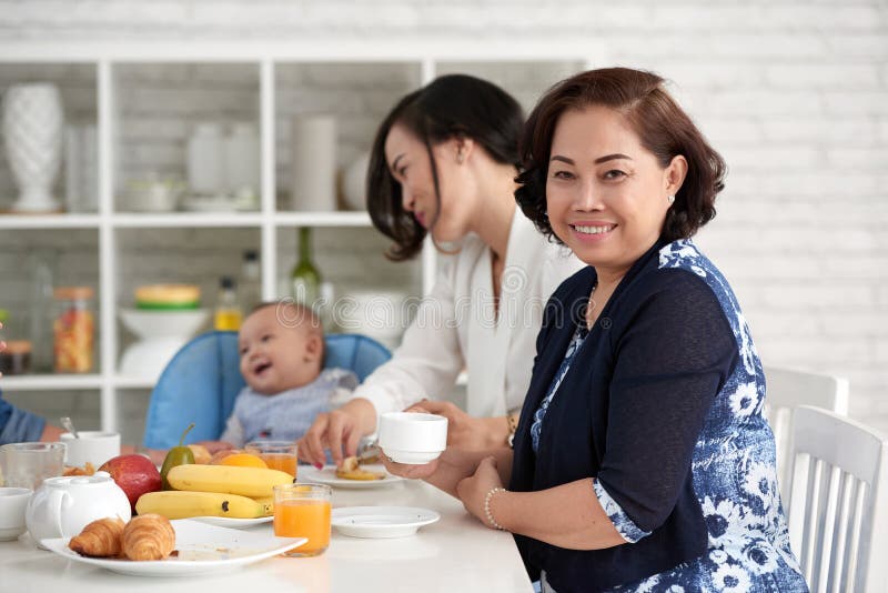 Elegante Asiatin am Frühstückstische mit Familie stockfotos Elegante Asiatin am Frühstückstische mit Familie stockfotos