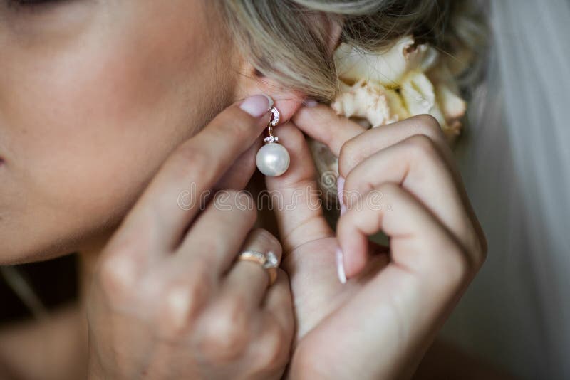 Elegante blondebruid die op oorringenclose-up zetten, die voorbereidingen treffen voor stock fotografie Elegante blondebruid die op oorringenclose-up zetten, die voorbereidingen treffen voor stock fotografie